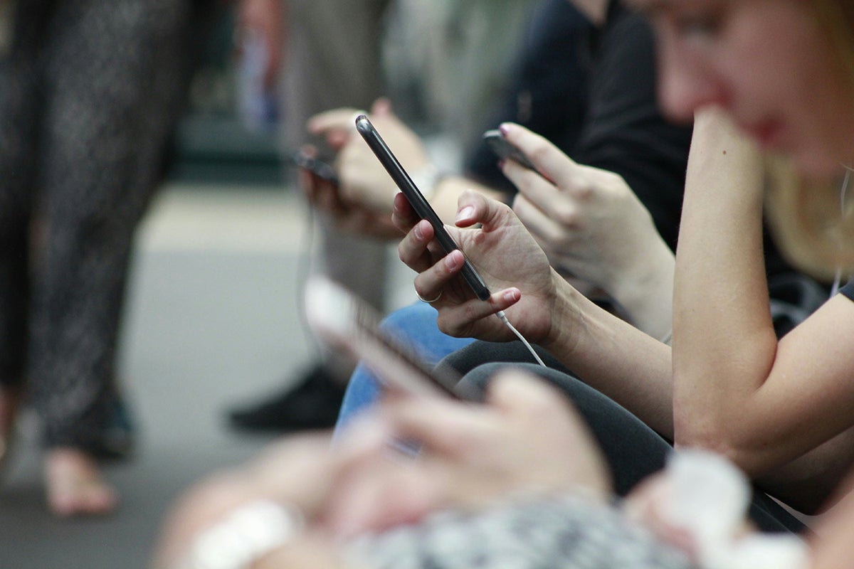 People sitting together, all using smartphones, focused on their screens.
