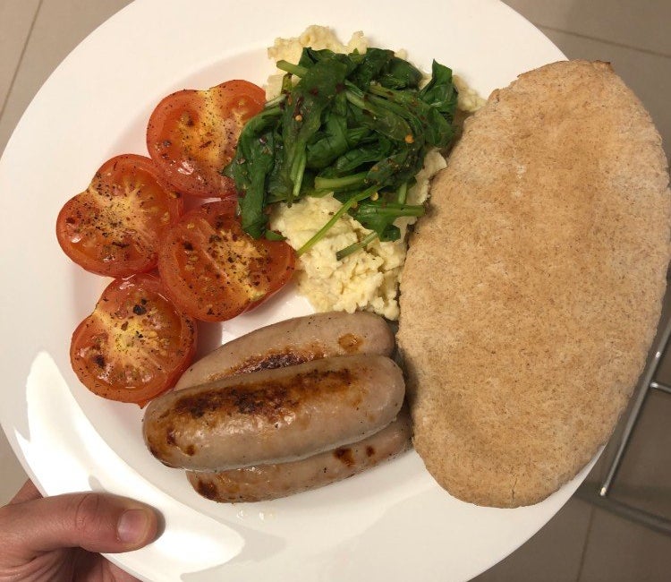 Plate of sausages, grilled tomatoes, spinach, scrambled egg and a wholemeal pitta