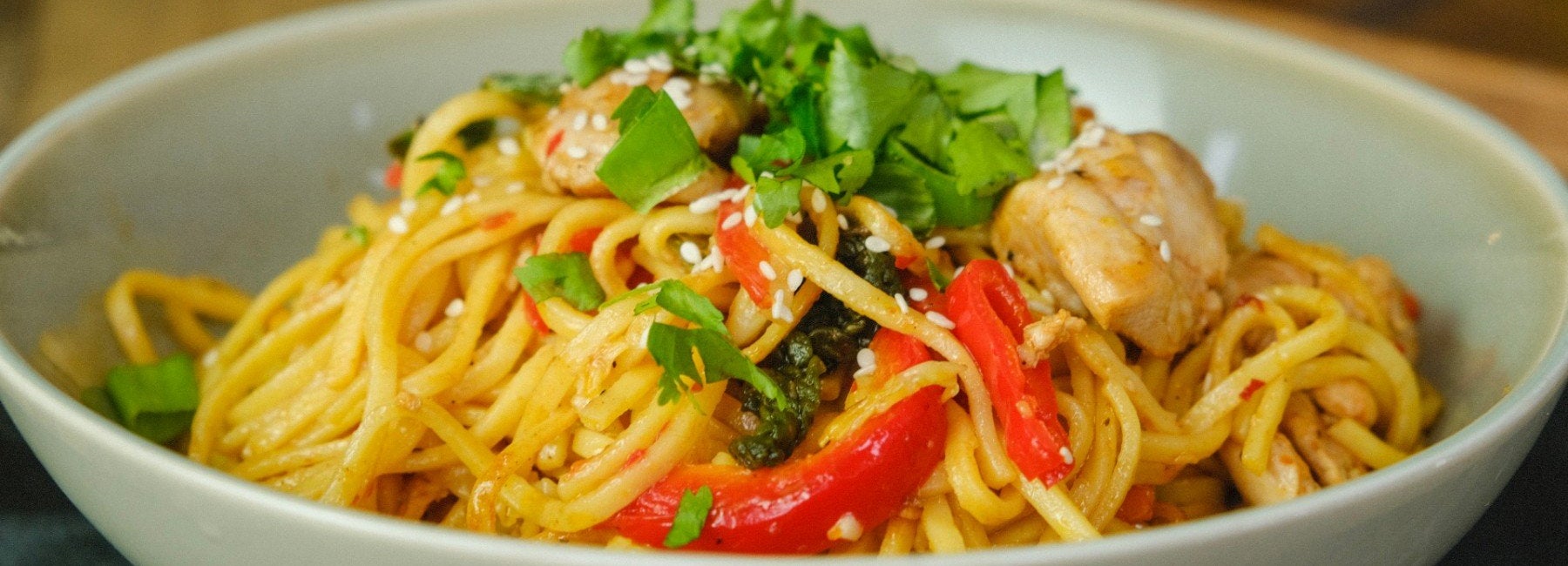 Bowl of sweet chilli chicken noodles with peppers and coriander