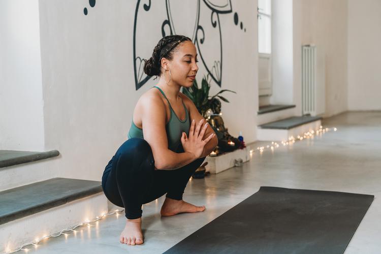 Woman in garland pose, squatting with her palms together
