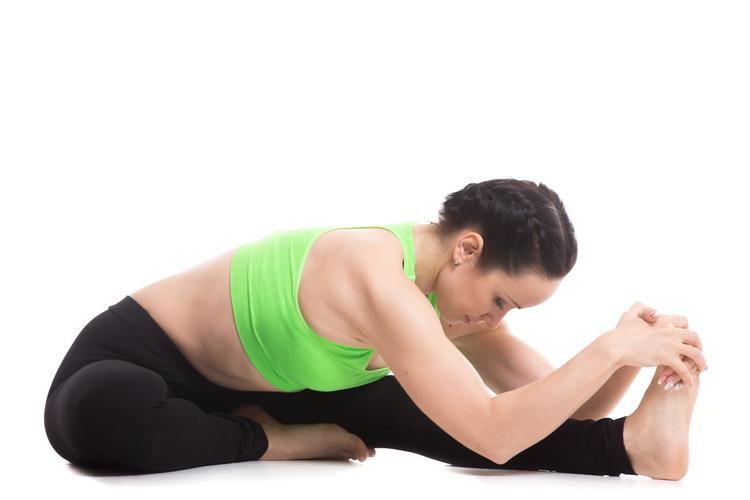 Woman in head to knee pose, stretching over one leg