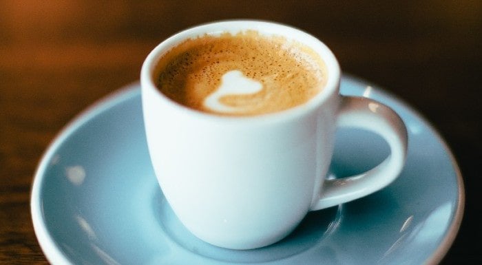 Cup of coffee with latte art on a blue saucer