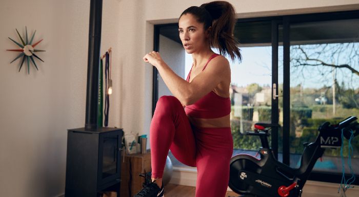 Woman in red activewear doing high knees at home