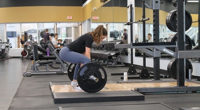 Woman lifting a barbell from the floor in a gym
