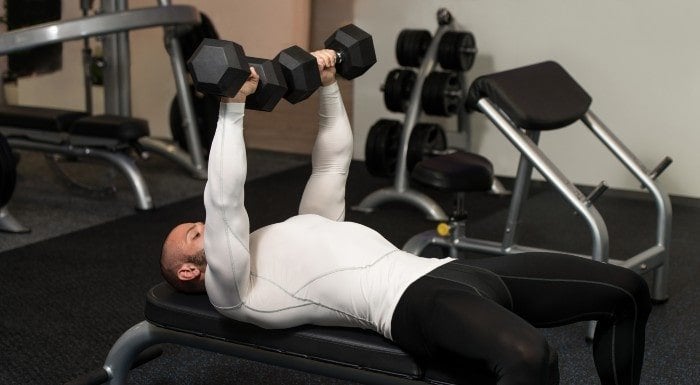 Man doing a dumbbell bench press on a flat bench
