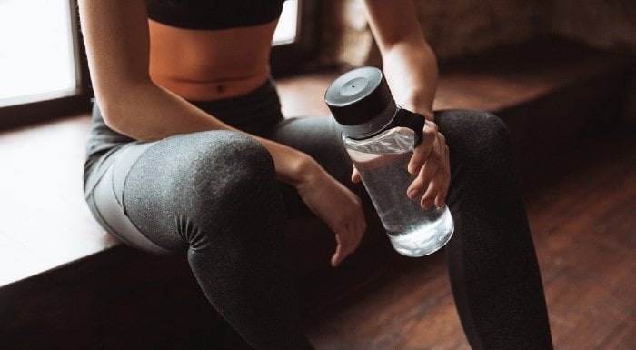Woman sitting on a step holding a water bottle