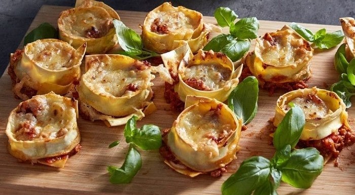 Vegan lasagne cups with basil on a wooden board