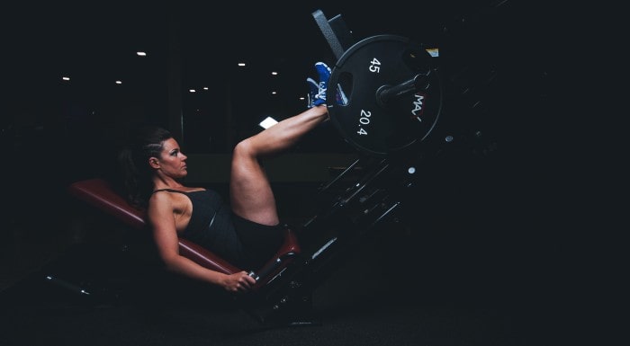 Woman using a leg press machine in a dark gym