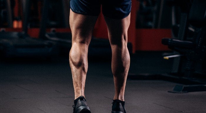 Close-up of a man's calf muscles as he stands in the gym