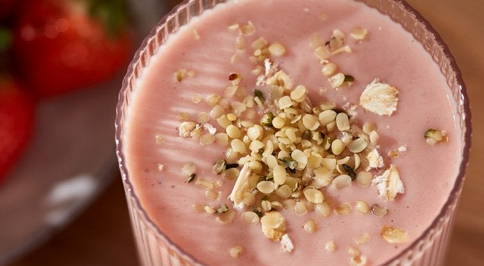 Strawberry protein smoothie topped with hemp seeds and oats