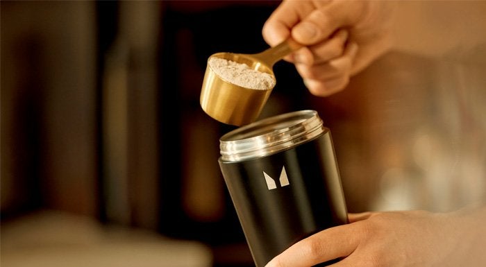 Scoop of pre-workout powder being added to a black Myprotein shaker