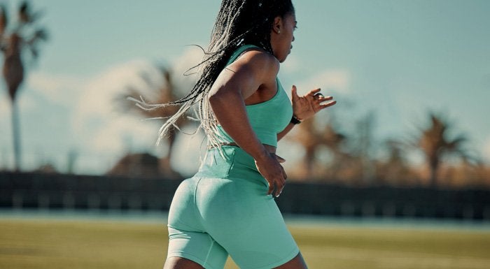 Woman in green activewear sprinting on a track