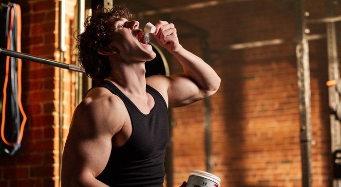 Man dry scooping pre-workout powder in the gym
