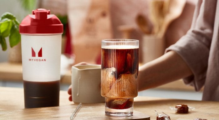 Glass of iced coffee next to a Myvegan shaker