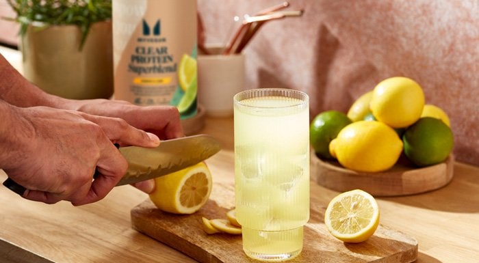 Lemons being sliced next to a glass of Myvegan Clear Vegan Protein