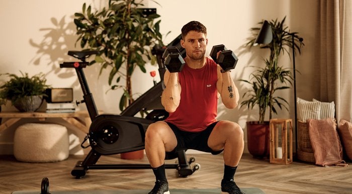 Man doing a dumbbell squat at home
