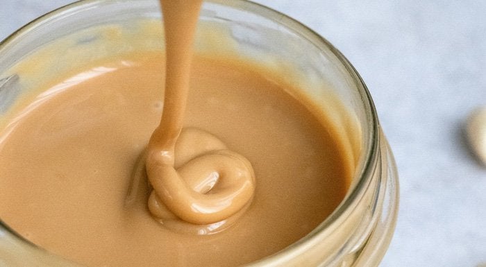 Peanut butter being stirred in a jar