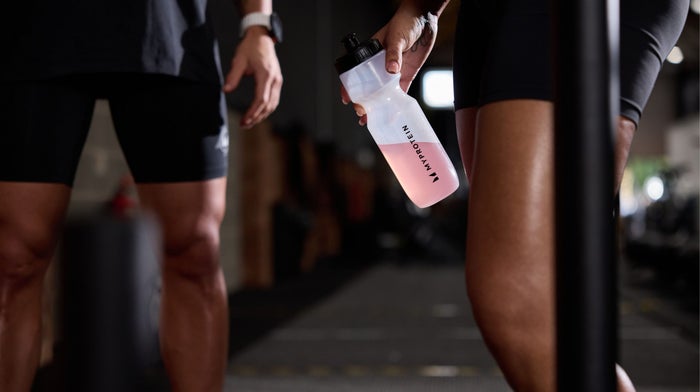 Two people in the gym, one holding a Myprotein water bottle