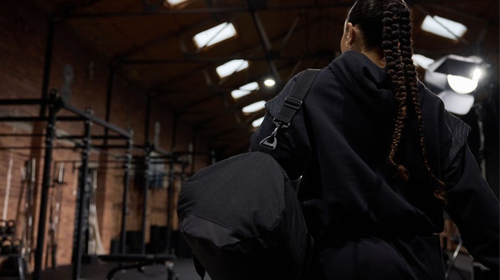 Woman with a gym bag walking into a gym
