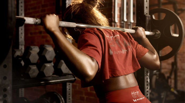Woman doing a barbell back squat in the gym