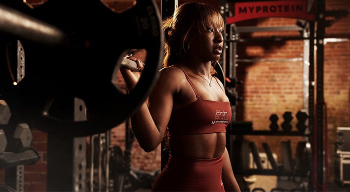 Woman lifting a barbell onto her shoulders in the gym