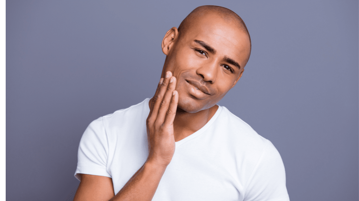 A man in a white t-shirt touches his face against a purple background | Gillette UK