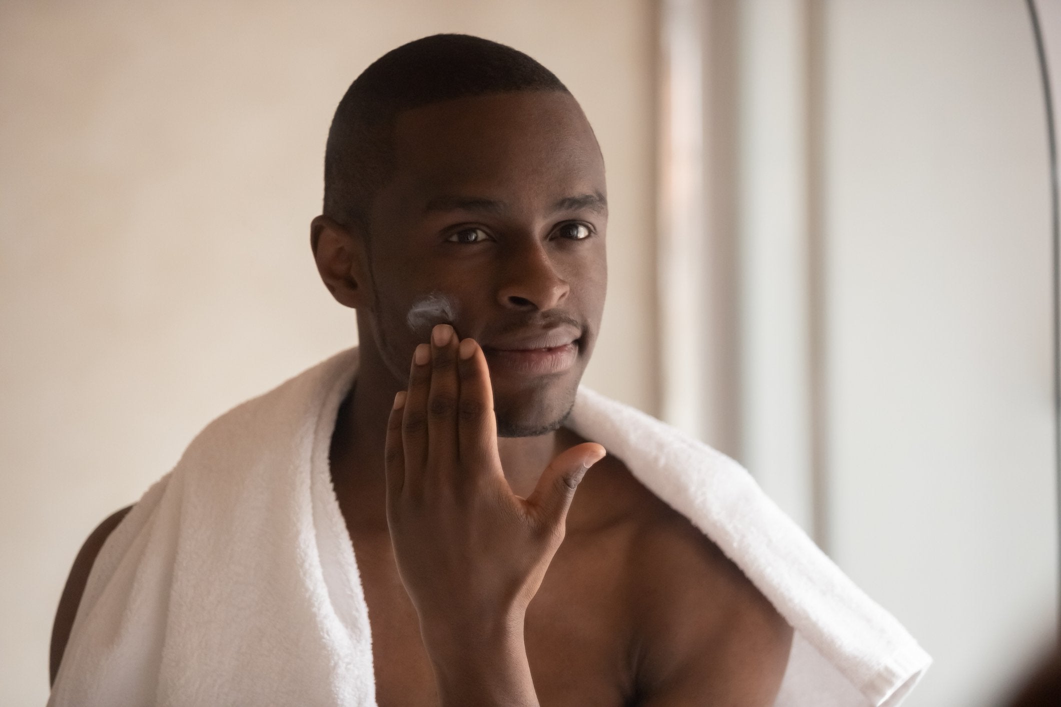man with stubble beard applies moisturising balm