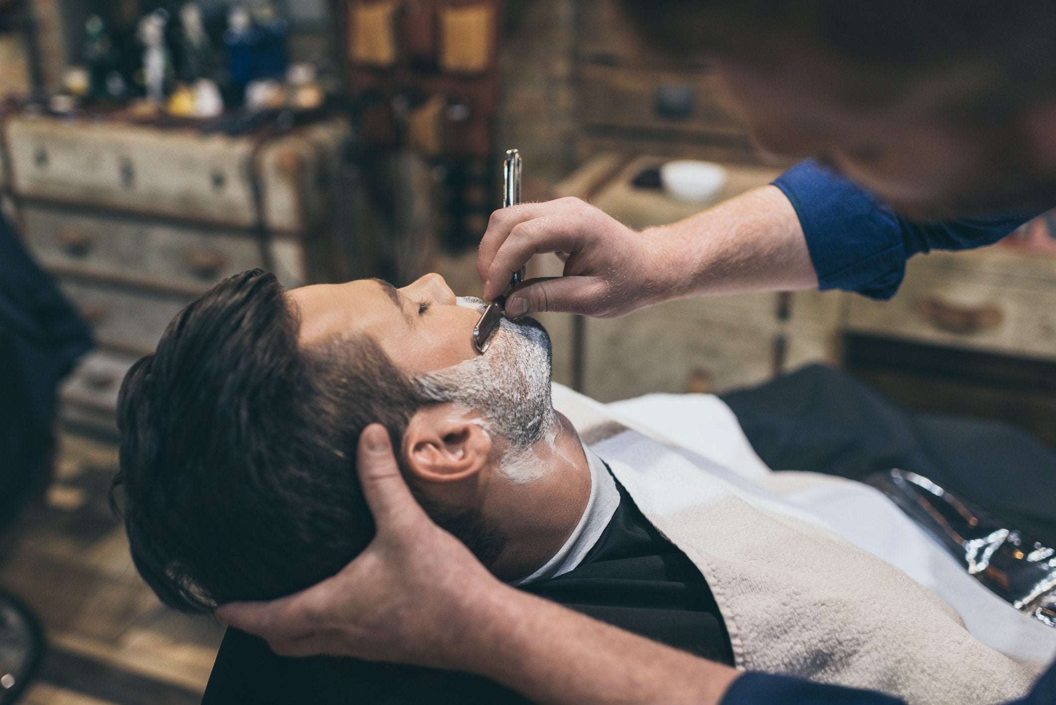 barber doing against the grain shaving with straight edge razor