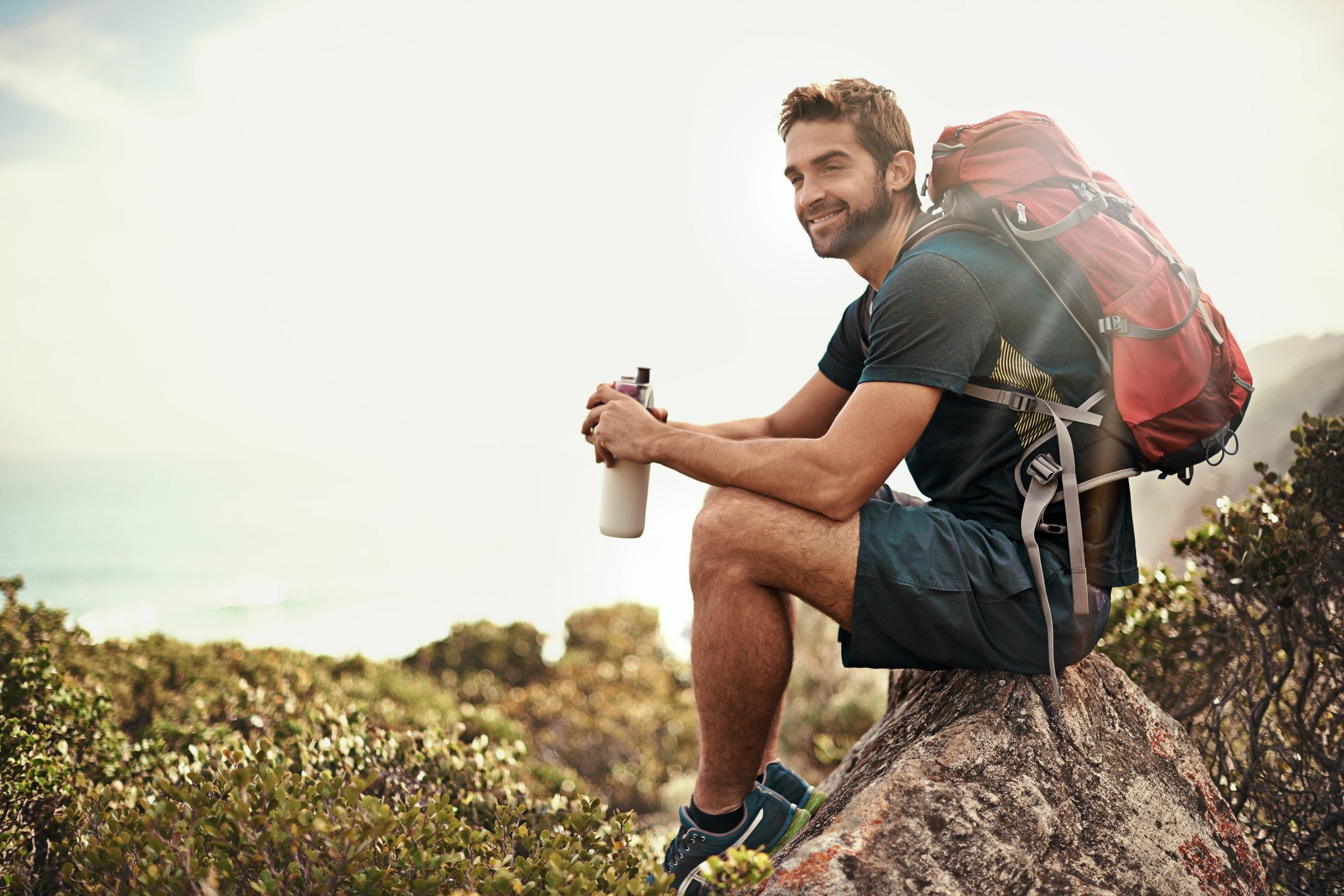 A man sits outside on a rock, freshly groomed thanks to his intimate shaving kit | Gillette UK