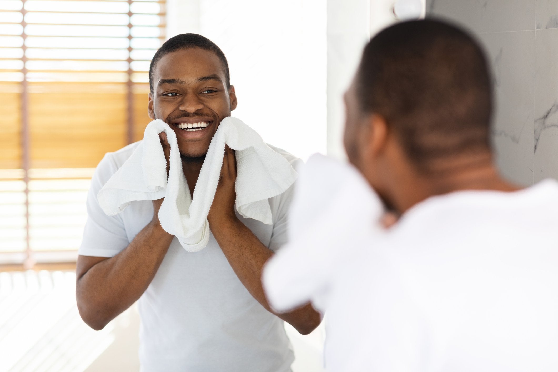 A clean-shaven man smiles in the mirror after using his useful shaving gift | Gillette UK