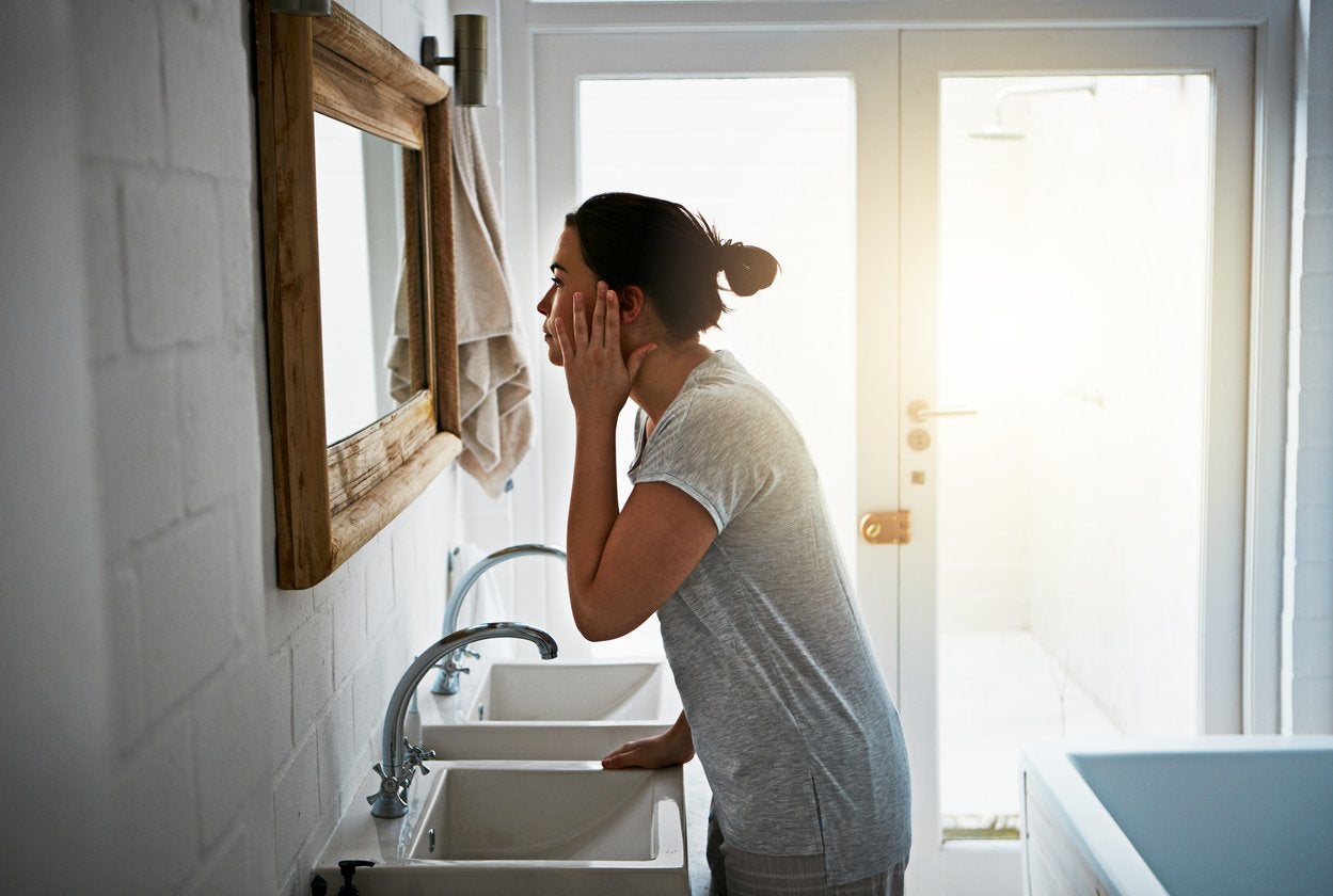Woman stood over a sink looking at her reflection before dermaplaning | Gillette Venus UK