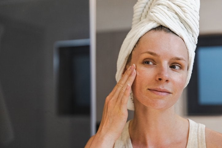 Woman applying dermaplaning Skin Care Hydration Serum to her face and looking in the mirror | Gillette Venus UK