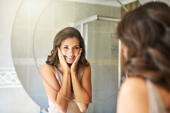 Woman smiling while looking into a mirror after dermaplaning | Gillette Venus UK
