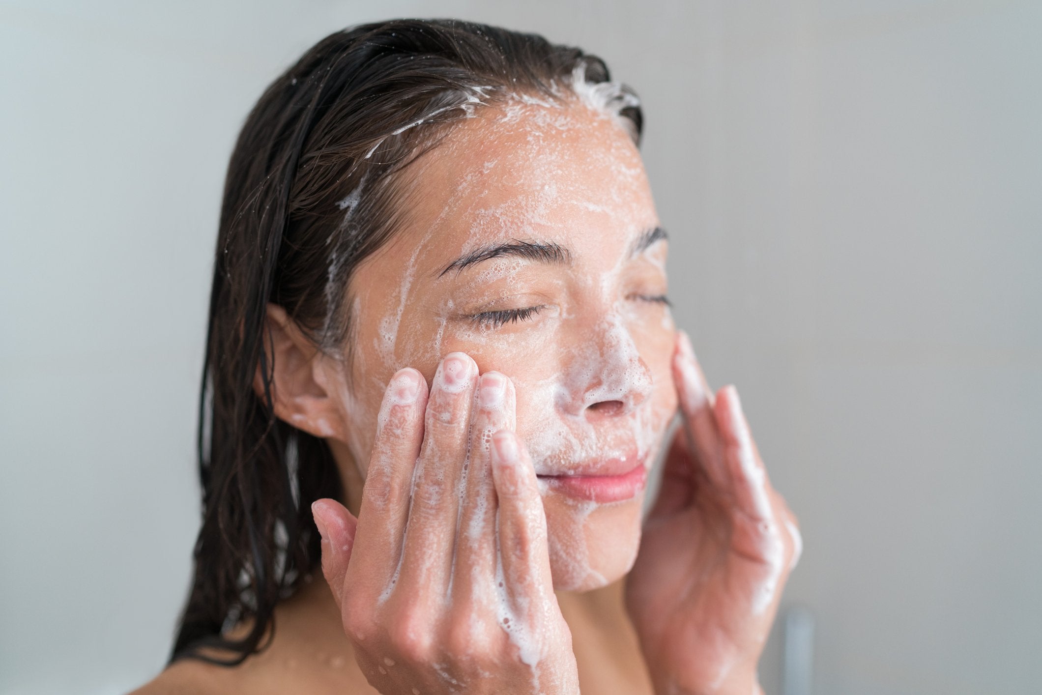 Woman cleansing face with water and cleanser ready for dermaplaning at home | Gillette Venus UK