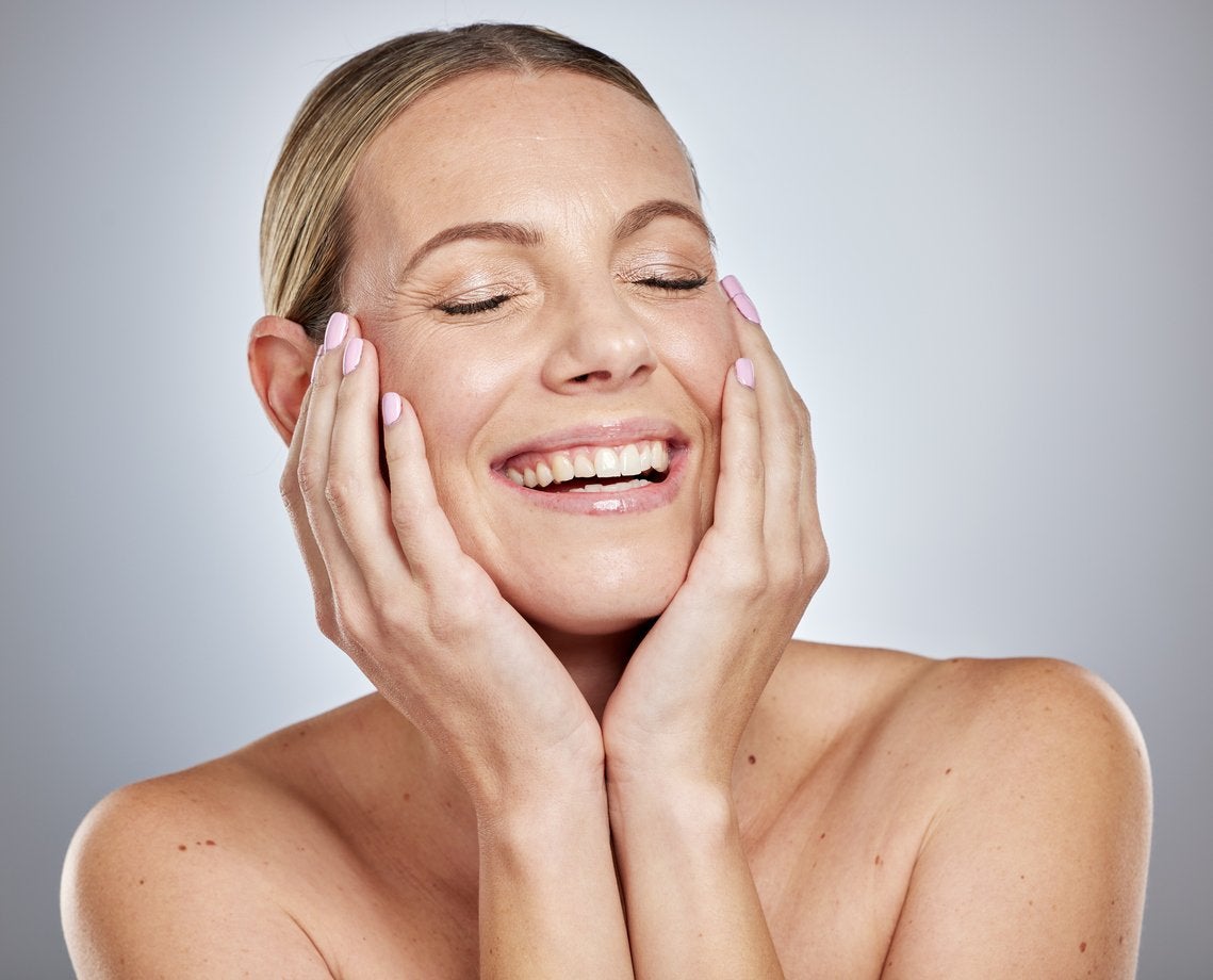 Smiling woman touching her clear skin after dermaplaning | Gillette Venus UK