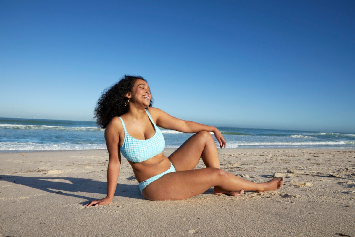 A woman relaxes on a beach in a blue bikini | Gillette Venus UK