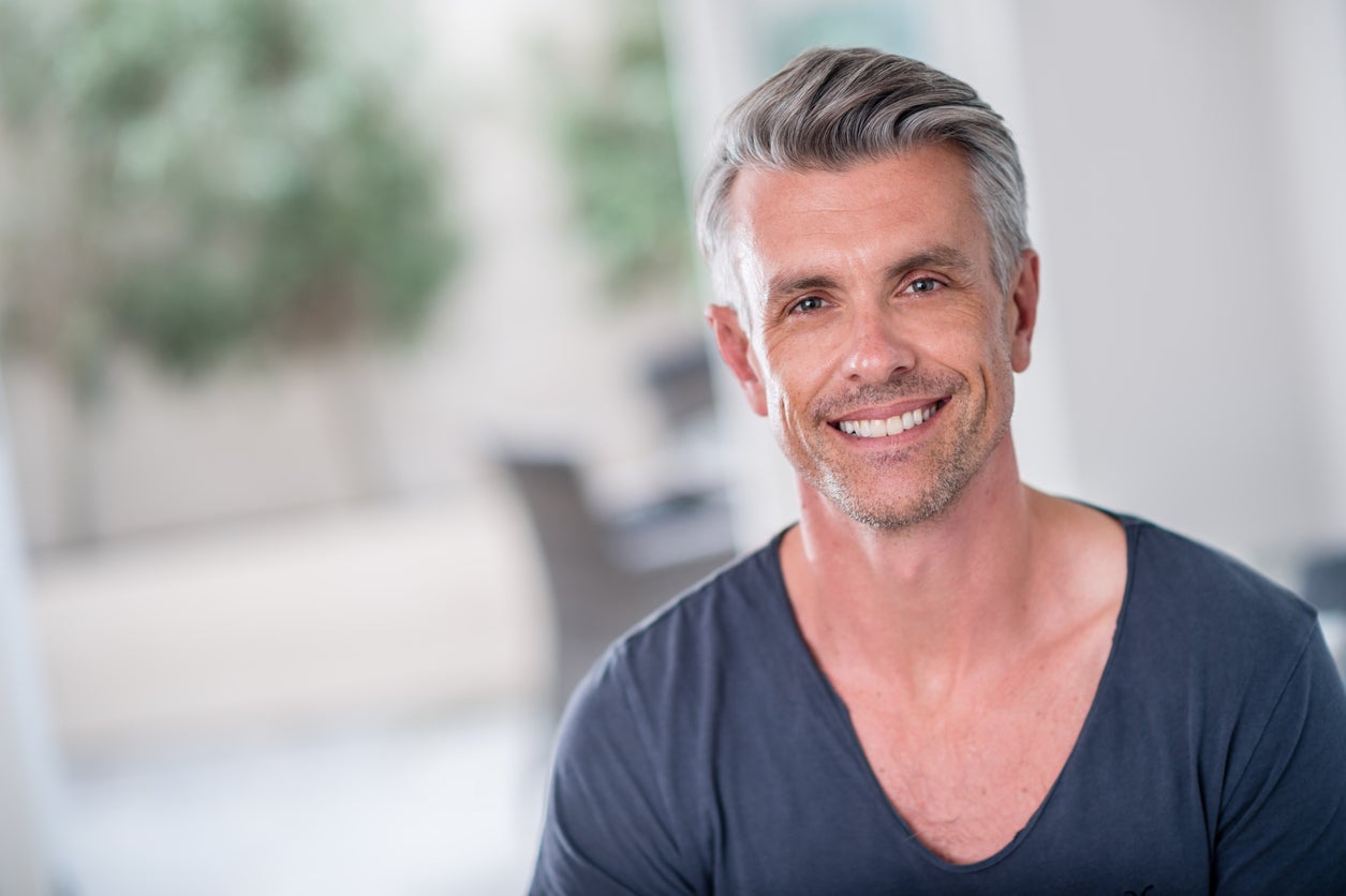 Man with grey comb-over hairstyle smiling
