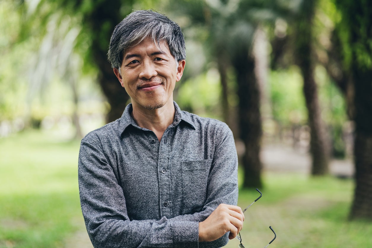 Man with mid-length grey hair and his arms folded, smiling at the camera