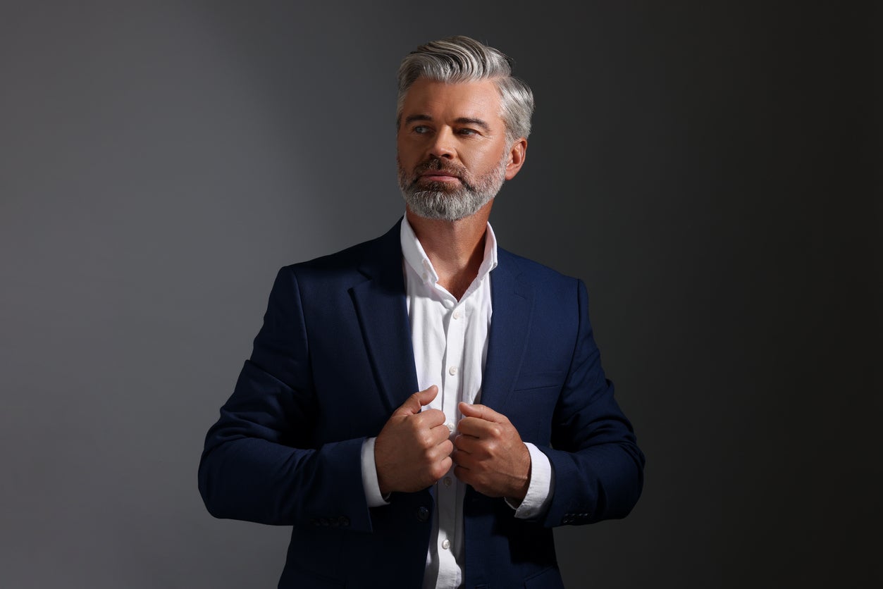 Confident man with grey quiff adjusting his suit lapels