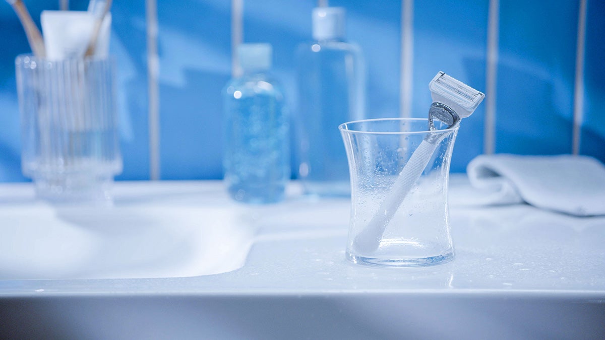 A white razor in a glass on the side of the bathroom sink | Gillette Venus UK
