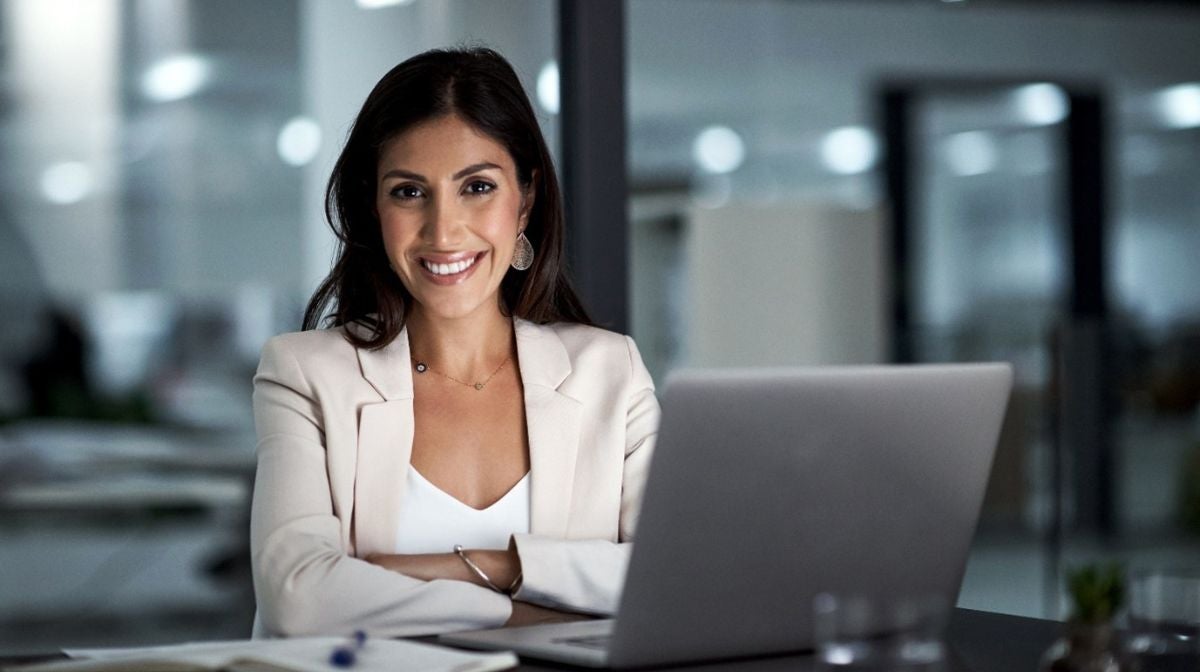 A woman smiles, wearing a natural, long-lasting makeup look at work
